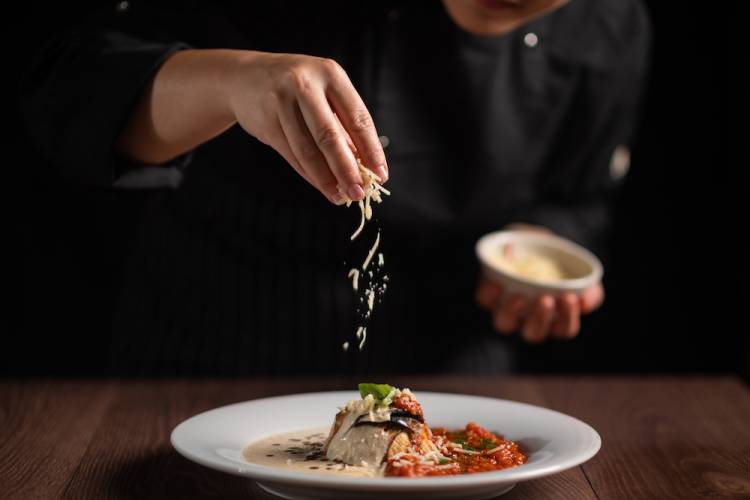 Chef sprinkling cheese onto a pasta dish