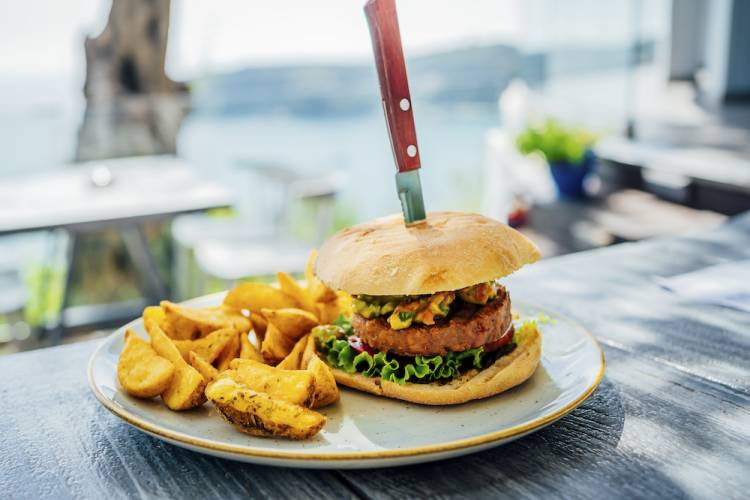 burger and fries on outdoor table by water